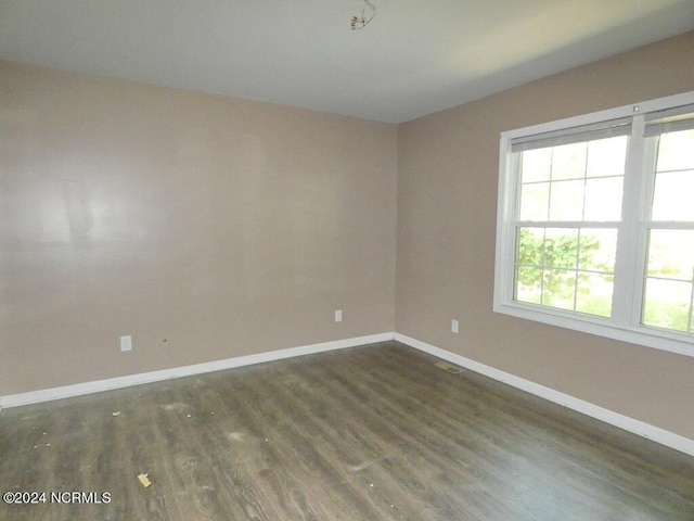 unfurnished room featuring visible vents, baseboards, and dark wood-style flooring