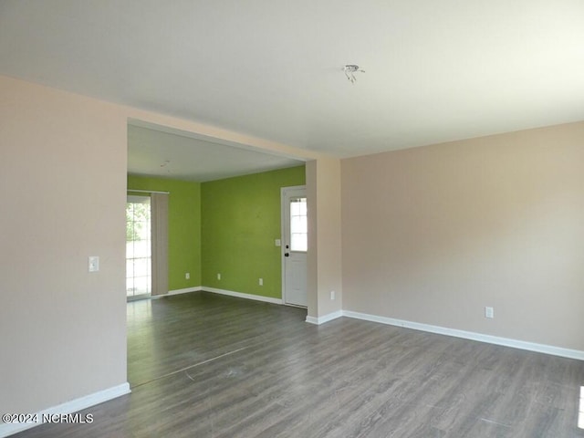 spare room featuring baseboards and dark wood-style flooring