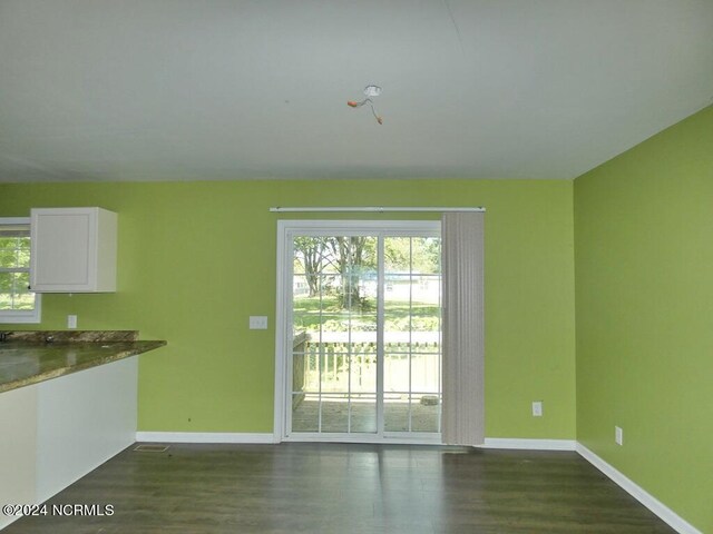 unfurnished living room featuring baseboards and dark wood-style flooring