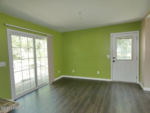 interior space with visible vents, baseboards, a healthy amount of sunlight, and dark wood-style floors