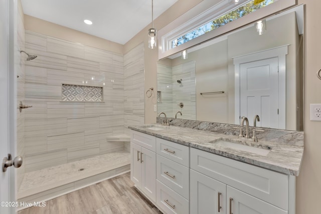 bathroom with tiled shower, wood-type flooring, and vanity