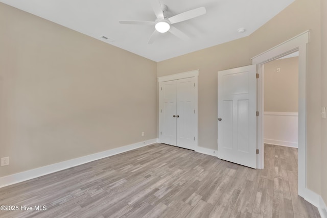 unfurnished bedroom featuring light wood-type flooring, ceiling fan, and a closet