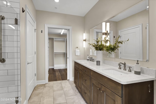 bathroom with baseboards, double vanity, a sink, and tile patterned floors