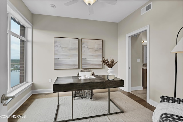 office space with a ceiling fan, wood finished floors, baseboards, and visible vents