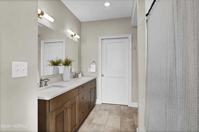 bathroom with baseboards, double vanity, a sink, and tile patterned flooring