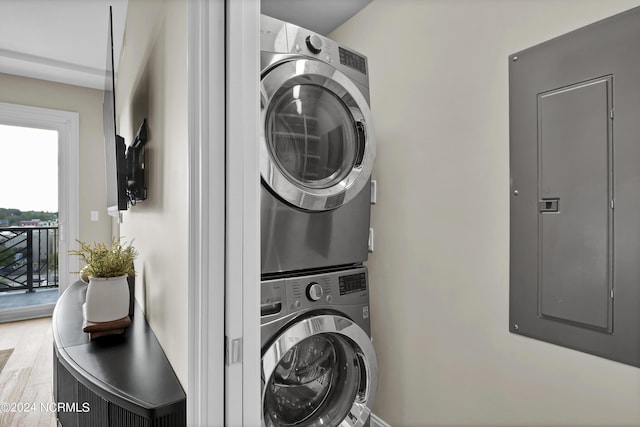 washroom featuring stacked washer and clothes dryer, wood finished floors, laundry area, and electric panel