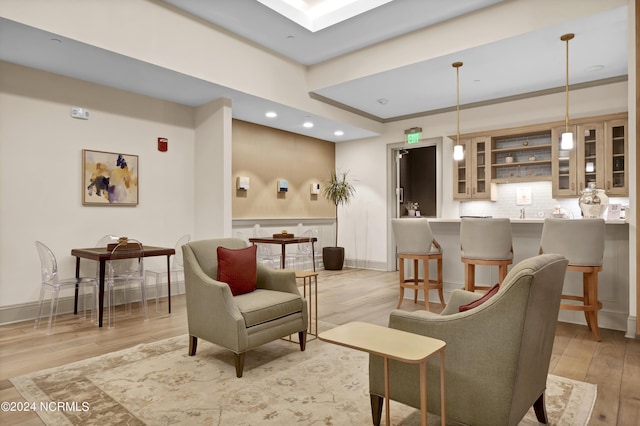 living area featuring baseboards, light wood-style flooring, indoor wet bar, and recessed lighting