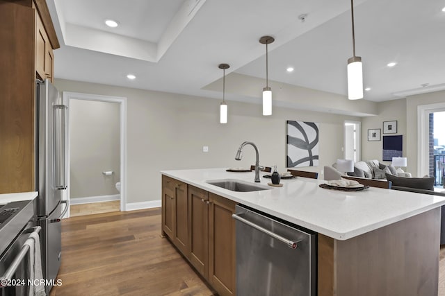 kitchen with recessed lighting, stainless steel appliances, a center island with sink, a sink, and wood finished floors