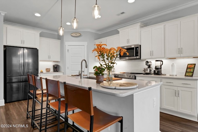 kitchen featuring stainless steel appliances, white cabinets, and a center island with sink