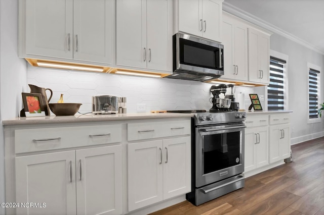 kitchen with tasteful backsplash, dark hardwood / wood-style floors, stainless steel appliances, ornamental molding, and white cabinetry