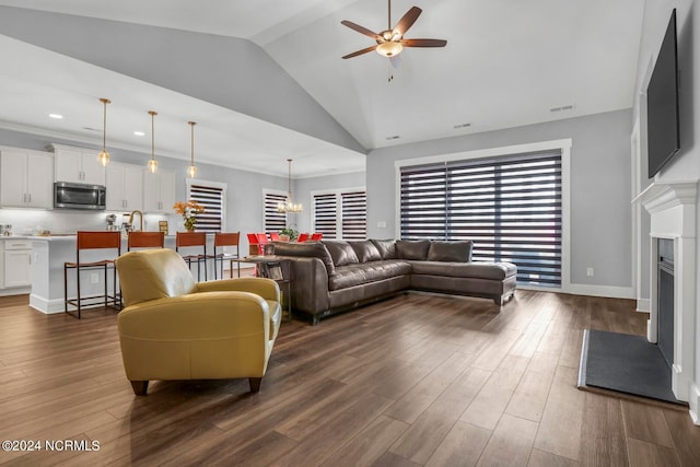 living room featuring ceiling fan with notable chandelier, crown molding, high vaulted ceiling, and dark hardwood / wood-style flooring