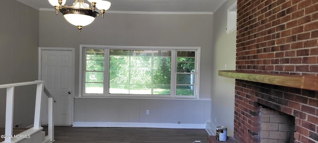 unfurnished living room featuring a fireplace, crown molding, dark hardwood / wood-style flooring, and a notable chandelier