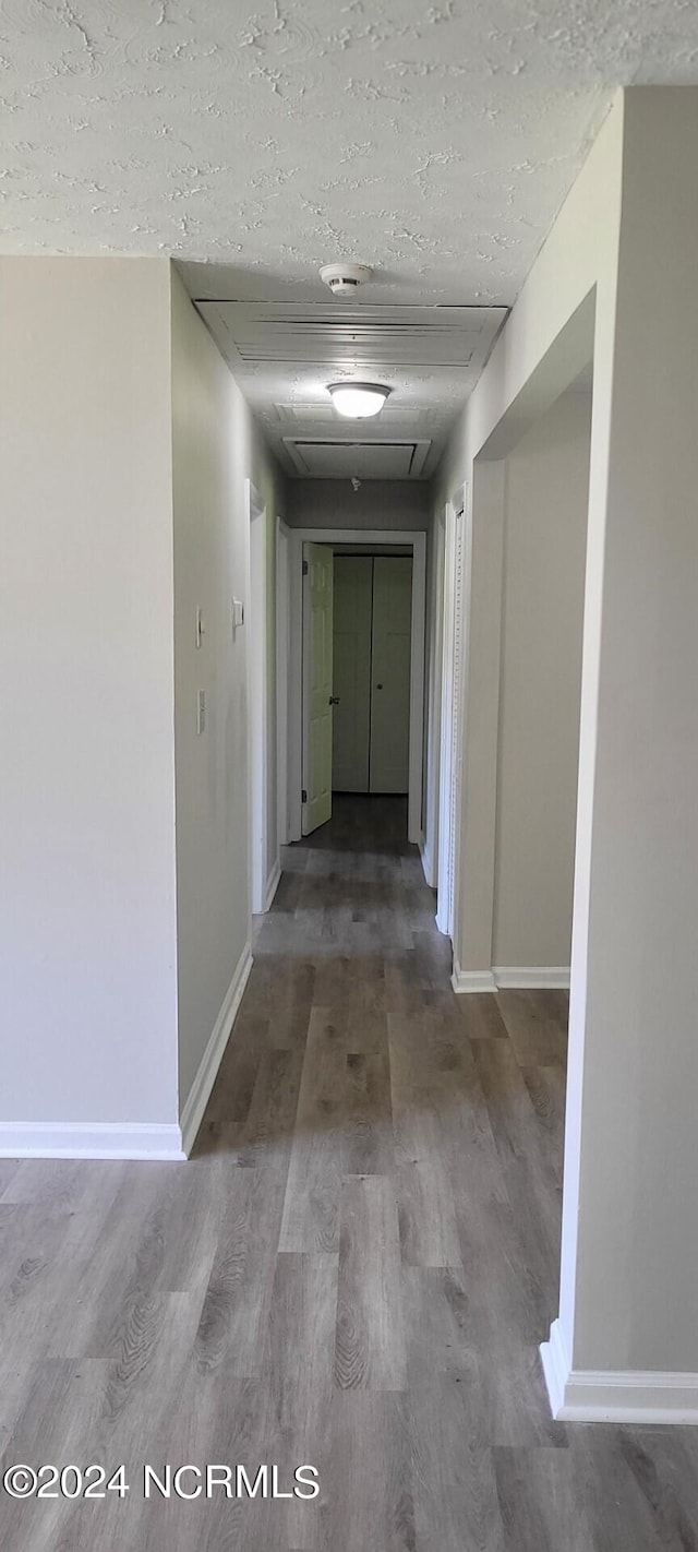 hallway with hardwood / wood-style flooring and a textured ceiling