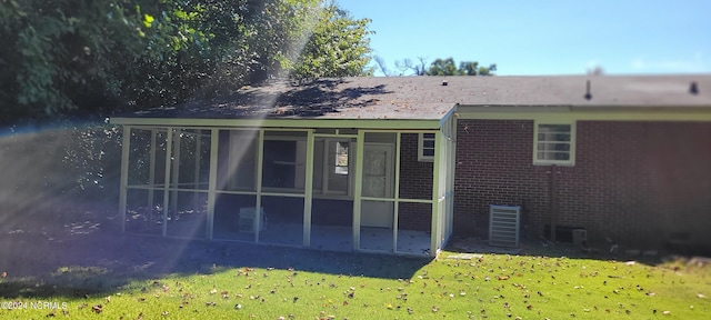 rear view of house featuring a yard, central AC unit, and a sunroom