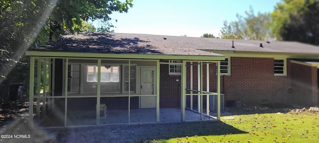 back of property featuring a sunroom and a lawn