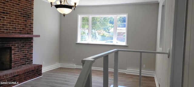 interior space with a textured ceiling, a fireplace, a notable chandelier, wood-type flooring, and ornamental molding