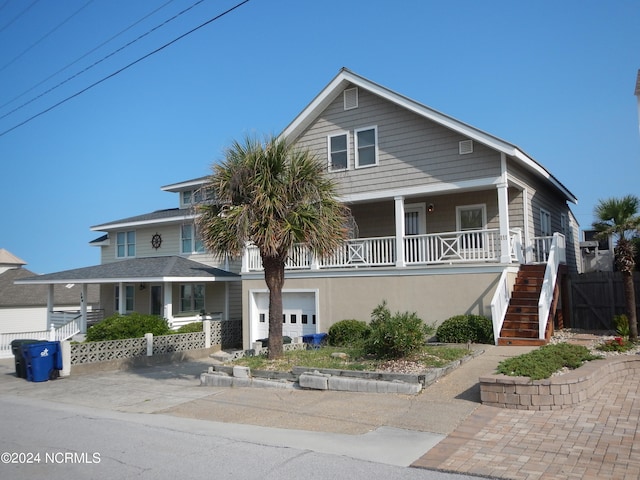 view of front of house with stairs, driveway, a porch, and a garage