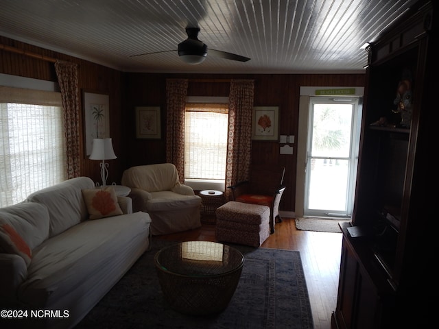 living room featuring wood walls, ceiling fan, hardwood / wood-style flooring, and a healthy amount of sunlight