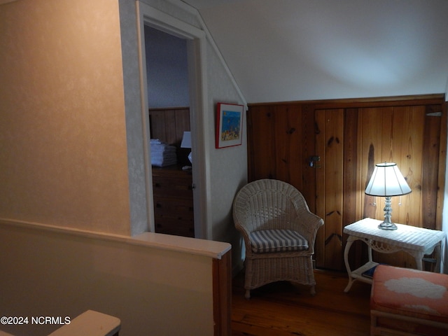 sitting room with hardwood / wood-style floors and wooden walls