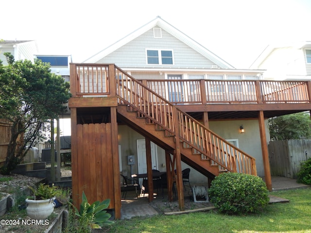 back of property featuring a yard, a deck, and a patio