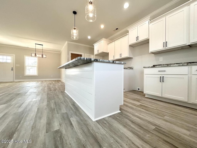 kitchen featuring decorative light fixtures, a center island, white cabinetry, and light hardwood / wood-style flooring