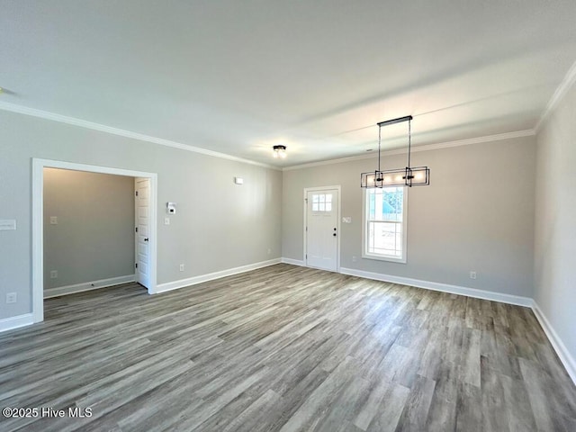 empty room with hardwood / wood-style flooring, crown molding, and a chandelier