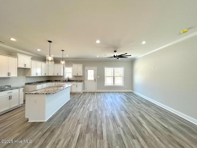 kitchen with ceiling fan, a healthy amount of sunlight, a kitchen island, decorative light fixtures, and white cabinets