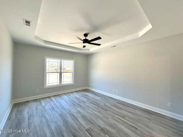 unfurnished room with hardwood / wood-style flooring, ceiling fan, and a tray ceiling