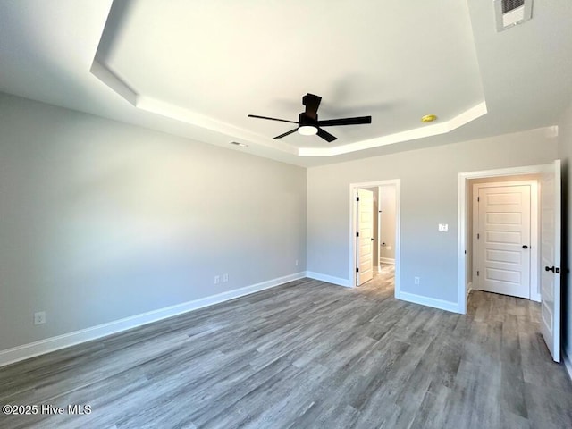 unfurnished bedroom featuring wood-type flooring, a raised ceiling, and ceiling fan