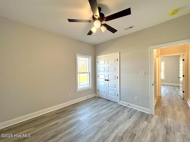 unfurnished bedroom featuring a closet, light hardwood / wood-style flooring, and ceiling fan