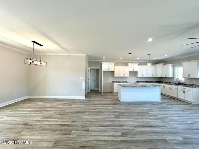 kitchen with white cabinets, a kitchen island, hanging light fixtures, and crown molding