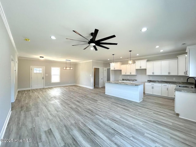 kitchen featuring white cabinetry, a center island, ceiling fan, sink, and light wood-type flooring