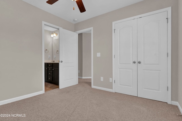 unfurnished bedroom with a closet, ceiling fan, light carpet, and ensuite bath