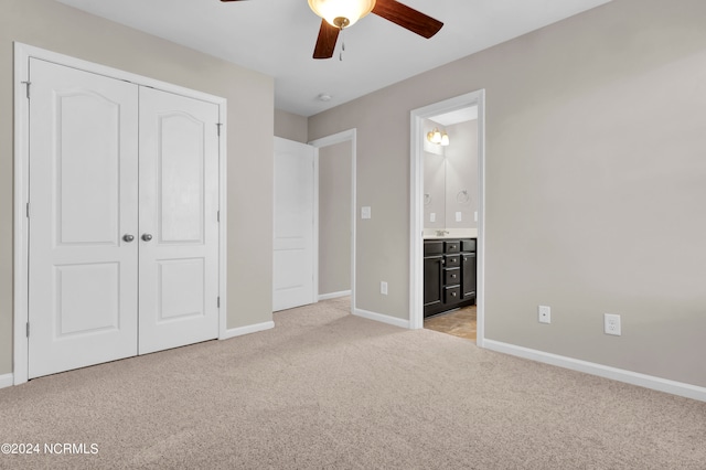 unfurnished bedroom featuring light carpet, ensuite bathroom, ceiling fan, and a closet