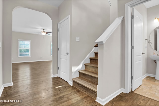 staircase with ceiling fan and wood-type flooring