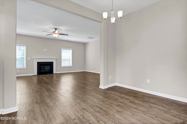 unfurnished living room with ceiling fan with notable chandelier and hardwood / wood-style flooring