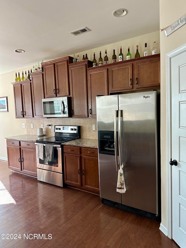 kitchen with backsplash, dark hardwood / wood-style floors, light stone countertops, and stainless steel appliances