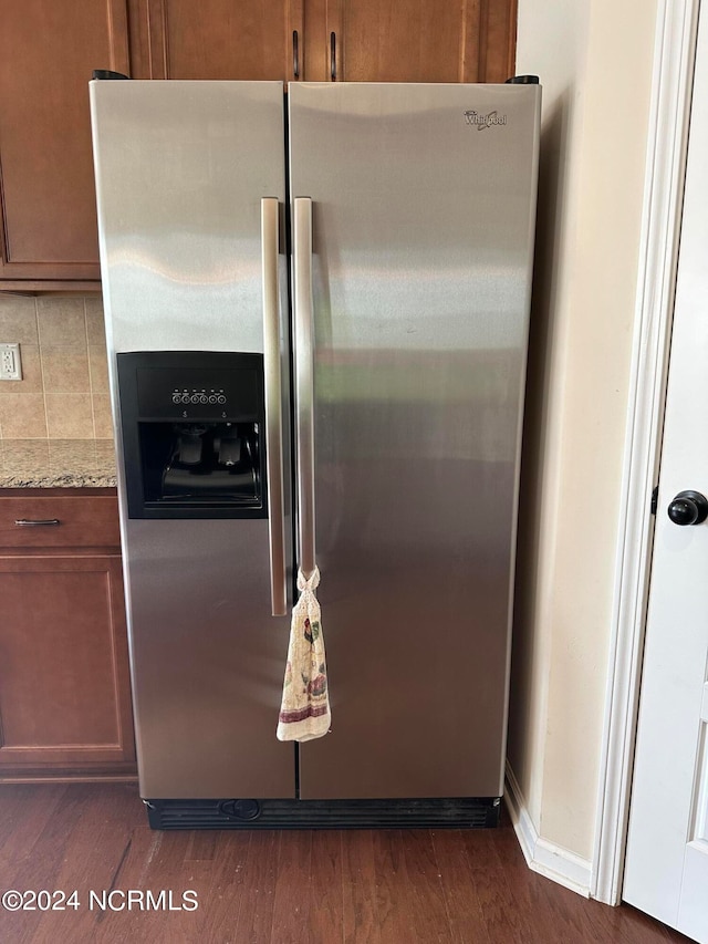 room details featuring tasteful backsplash, light stone countertops, dark hardwood / wood-style floors, and stainless steel refrigerator with ice dispenser