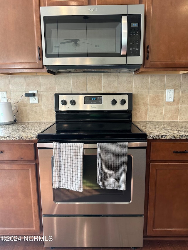 kitchen with light stone counters, backsplash, and appliances with stainless steel finishes