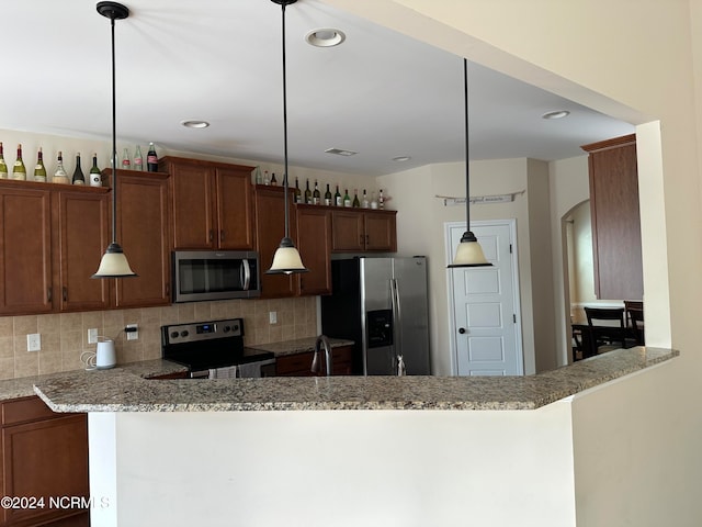 kitchen featuring light stone countertops, stainless steel appliances, kitchen peninsula, pendant lighting, and decorative backsplash