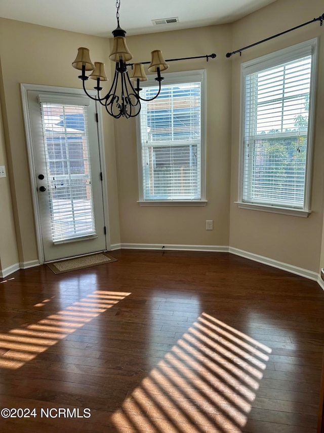 unfurnished dining area featuring dark hardwood / wood-style floors and an inviting chandelier