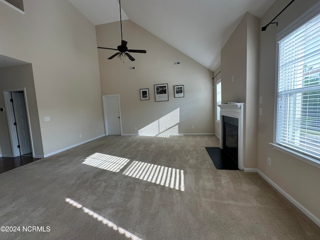 unfurnished living room with light colored carpet, high vaulted ceiling, plenty of natural light, and ceiling fan