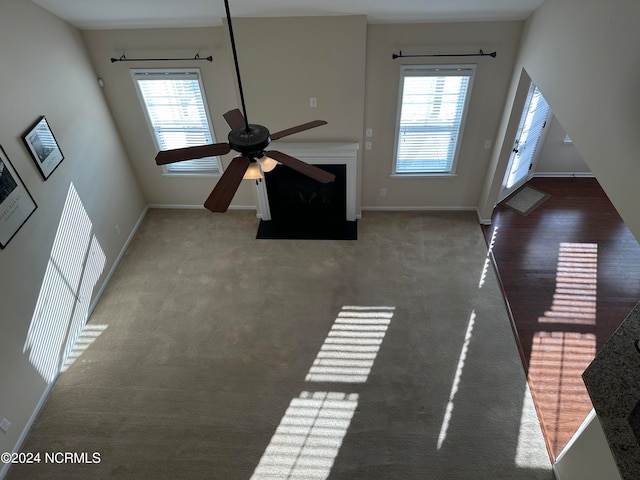 unfurnished living room featuring carpet, plenty of natural light, and ceiling fan