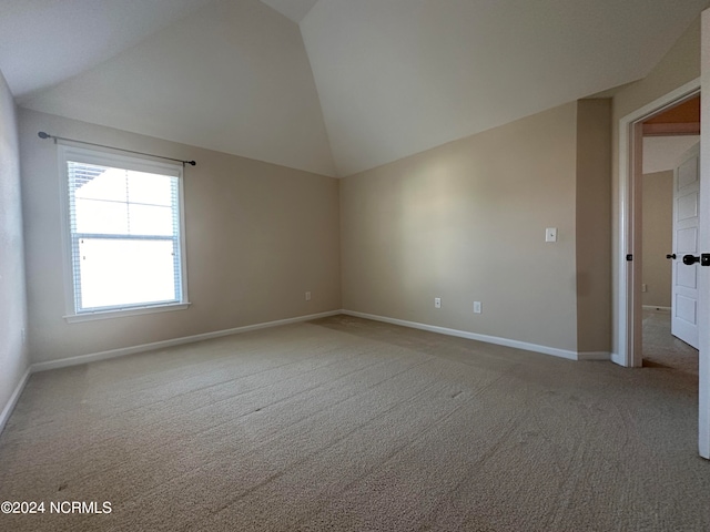 carpeted empty room with vaulted ceiling