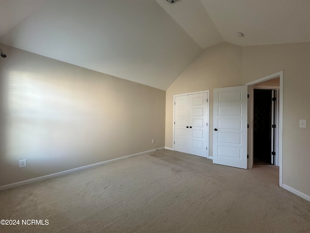 unfurnished bedroom featuring light carpet, a closet, and lofted ceiling