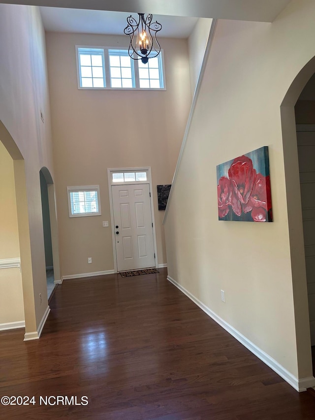 foyer with a high ceiling, an inviting chandelier, and dark wood-type flooring