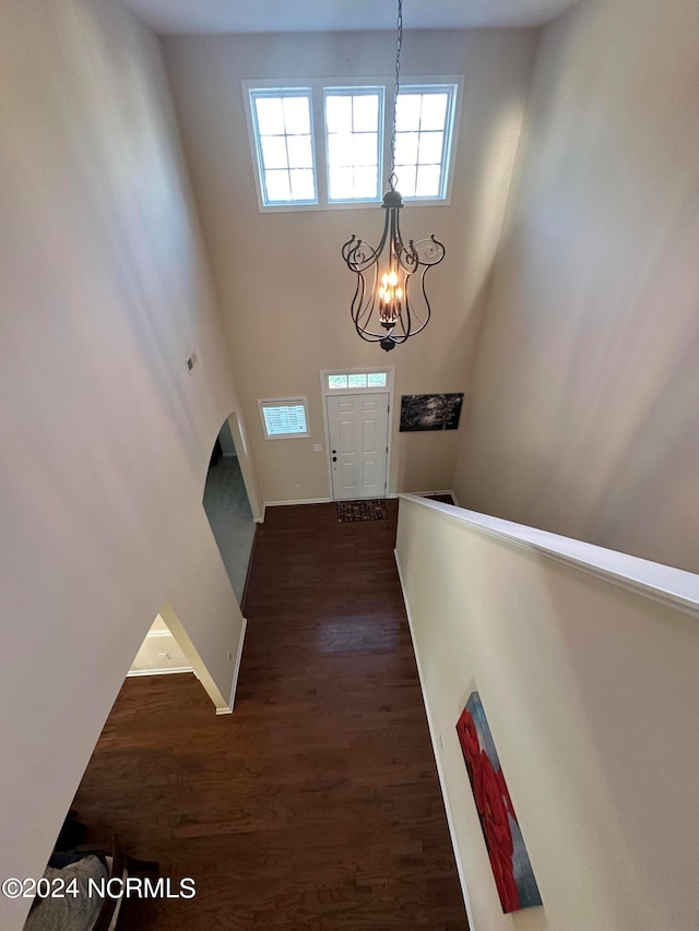 foyer with a high ceiling, an inviting chandelier, and dark wood-type flooring