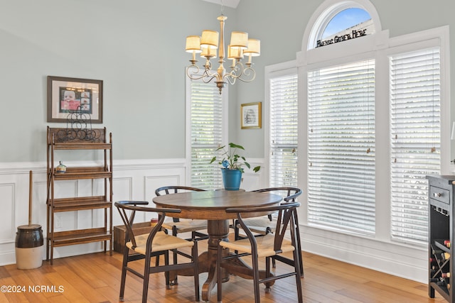 dining area featuring light hardwood / wood-style flooring, a high ceiling, and a notable chandelier