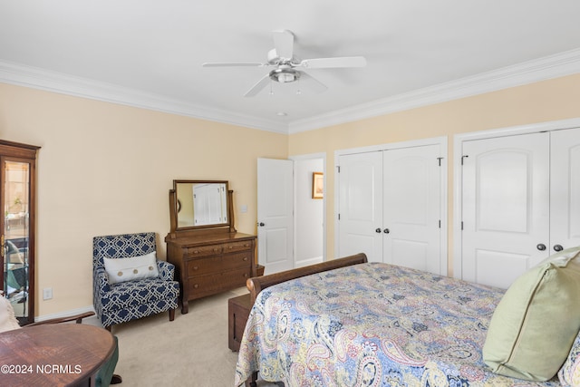 bedroom featuring light colored carpet, ceiling fan, ornamental molding, and multiple closets