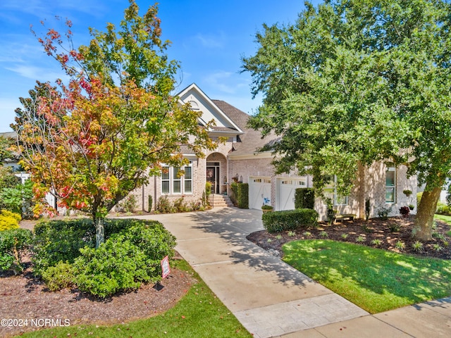 view of property hidden behind natural elements with a garage and a front yard